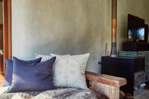 a room with a bed with pillows and a bench at Kanuka Terrace - Luxury Strawbale House in Kaikoura
