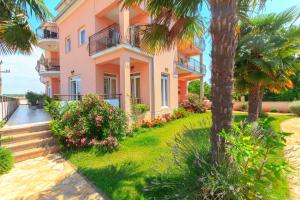 a pink apartment building with palm trees and flowers at Apartments 4 Palme in Funtana