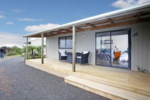 Casa con terraza con cama y mesa en Auckland Country Cottages, en Clevedon