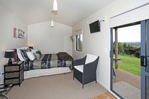 a bedroom with a bed and a sliding glass door at Auckland Country Cottages in Clevedon