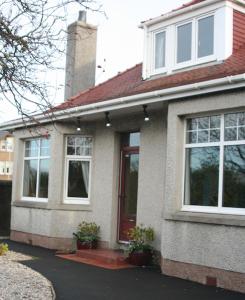 a white house with a red door and windows at Ramadale B&B in Stornoway