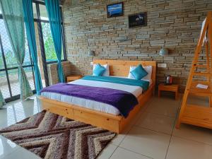 a bedroom with a wooden bed and a brick wall at Rudra Himalayan Retreat in Almora