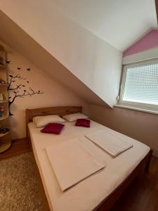a bedroom with a bed with red pillows and a window at Holiday Home Hodo in Sarajevo