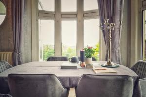 a dining room table with chairs and a large window at Alma Cliffe Guest House in Barnoldswick