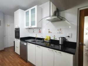 a kitchen with white cabinets and a black counter top at Penthouse by JJ in Bangkok