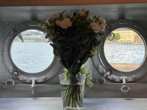 a vase of flowers sitting on a table with two windows at Den Röda Båten in Stockholm