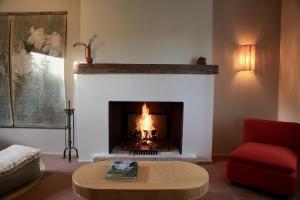 a living room with a fireplace and a red chair at CASAMAAS in Les Basses Masures