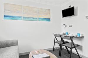 Zimmer mit einem Tisch, einem Bett und einem TV in der Unterkunft Cwtch on the Coast in Swansea