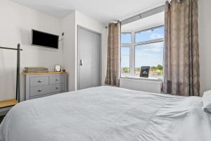 a white bedroom with a bed and a window at Cwtch on the Coast in Swansea