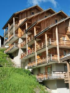 an apartment building with wooden balconies on a hill at residence avec piscine ,chalet des rennes in Vars
