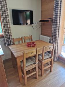 mesa de comedor de madera con sillas y TV en residence avec piscine ,chalet des rennes, en Vars