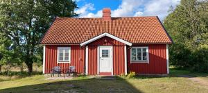 a red house with two chairs in front of it at Björkbacken Stuga in Markaryd