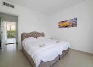 een slaapkamer met een groot bed met witte lakens bij אצולת הים - טבריה in Tiberias