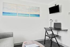 ein Zimmer mit einem Schreibtisch mit Laptop und Fernseher in der Unterkunft Cwtch on the Coast in Swansea + 4 Fotos