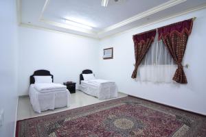 Cette chambre blanche comprend 2 lits et un tapis. dans l'établissement العييري للوحدات السكنية القصيم 1, à Quaniya