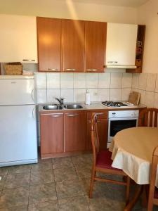 a kitchen with a white refrigerator and a table with chairs at Apartmani Luka in Korčula
