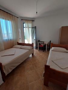 1 dormitorio con 2 camas, mesa y silla en Vila Flamuri, en Golem