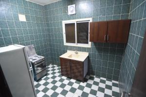 La salle de bains carrelée de couleur verte est pourvue d'un lavabo et d'un miroir. dans l'établissement العييري للوحدات السكنية القصيم 1, à Quaniya