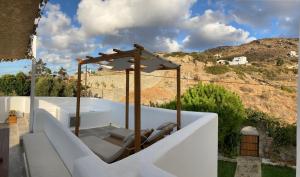 einen weißen Balkon mit einer Bank und einem Sonnenschirm in der Unterkunft Ninemia Naxos Suites in Naxos Chora