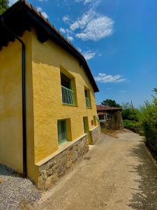 a yellow building with green windows and a dirt road at El Paraíso de Villar in Arriondas