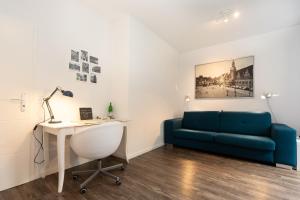 ein Wohnzimmer mit einem blauen Sofa und einem Schreibtisch in der Unterkunft L.E. Home in Leipzig