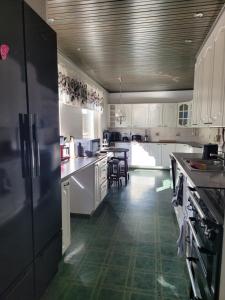 a kitchen with white cabinets and a black refrigerator at Niittyvilla Apartments in Jämsä