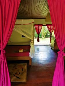een slaapkamer met rode gordijnen en een bed met een raam bij Chambres d'hôtes Villa Les Orchidées Chez Ago in Sainte Marie