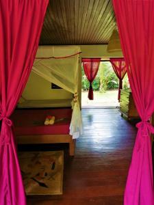 a bedroom with red curtains and a bed with a window at Chambres d'hôtes Villa Les Orchidées Chez Ago in Sainte Marie