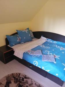 um quarto com uma cama com lençóis e almofadas azuis em Căsuța din pădure de la Câmpu lui Neag em Cîmpu lui Neag
