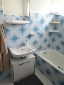 ザラカロシュにあるLívia Apartman - Zalakarosの青いタイル張りのバスルーム(シンク、バスタブ付)