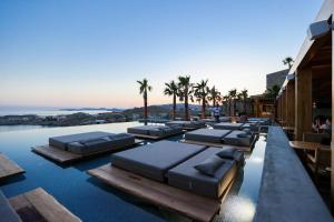 a swimming pool with chaise lounges on the water at Tropicana Hotel , Suites & Villas Mykonos in Paradise Beach