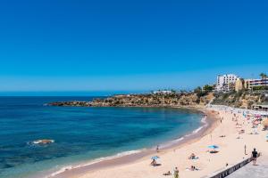 a beach with people on the sand and the ocean at T2 Tiles Apartment Estoril in Estoril