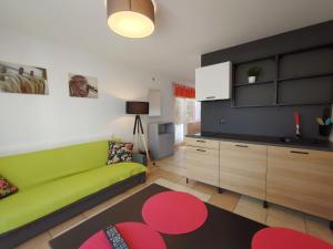 a living room with a green couch and a kitchen at Bungalow Kapitański in Jastrzębia Góra