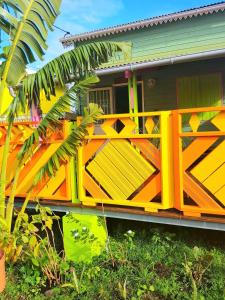 ein gelbes und orangefarbenes Haus mit einem Zaun davor in der Unterkunft Le Ti Citron Vert in Saint-Leu