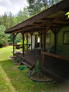 a wooden pavilion with a table and chairs on it at Domki holenderskie na Mazurach in Dźwierzuty