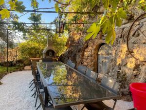 una mesa de cristal frente a una pared de piedra en Le jardin de Camille, en Cotignac