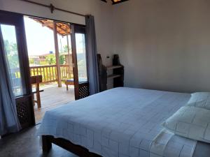 a bedroom with a white bed and a balcony at Apartamento do Manu in Atins