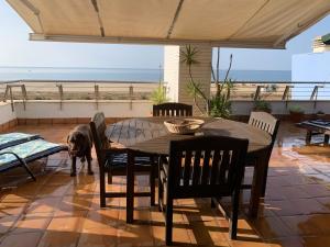 ein Hund steht auf einer Terrasse mit einem Tisch und Stühlen in der Unterkunft Espectacular Atico Frente Al Mar in Isla del Moral