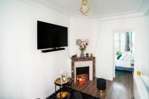 salon z kominkiem i telewizorem z płaskim ekranem w obiekcie Suite L'éclipse Paris, logement avec jacuzzi, à 10 minutes des Champs Elysées w mieście Levallois-Perret