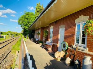 a train station with benches next to a brick building at Stoke Edith Station in Hereford