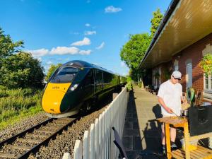 a man standing at a train station with a train at Stoke Edith Station in Hereford