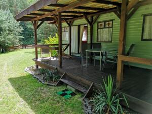 una terraza de madera al lado de una casa verde en Domki holenderskie na Mazurach en Dźwierzuty