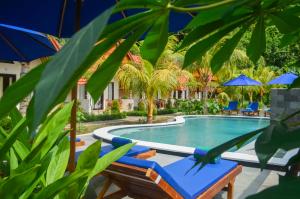 a swimming pool with lounge chairs and umbrellas at Penida Bay Village in Nusa Penida