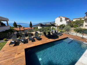 a swimming pool with lounge chairs and a house at Apartments Sky in Rijeka