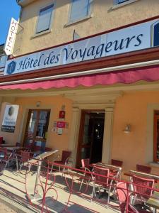 un bâtiment avec des tables et des chaises à l'extérieur dans l'établissement HOTEL DES VOYAGEURS, à Pont-de-Roide