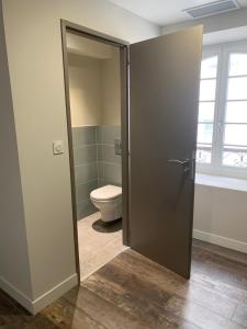 a bathroom with a toilet and a glass door at Les Appartements - Les Anges Béarnais I et Les Anges Béarnais II in Sauveterre