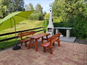a picnic table and two benches with an umbrella at Apartmány NIVA in Široká Niva