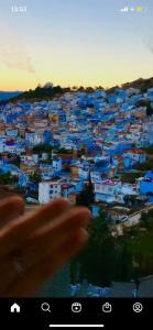 una mano apuntando a una ciudad con casas azules en Hotel Alkhalifa, en Chefchaouen