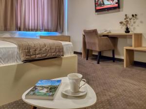 um quarto de hotel com uma cama e uma mesa com um livro em Hotel Argentum em Mostar