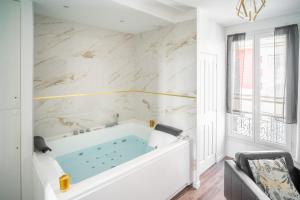 wanna w białej łazience z marmurowymi ścianami w obiekcie Suite L'éclipse Paris, logement avec jacuzzi, à 10 minutes des Champs Elysées w mieście Levallois-Perret